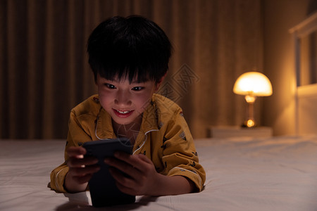 小男孩在黑暗中玩手机背景图片