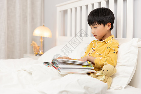 小男孩睡前在床上看书图片