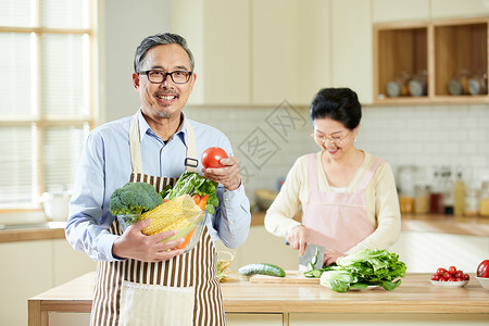 厨房里中老年男士手捧新鲜蔬菜高清图片