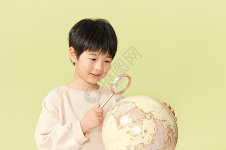 小男孩用放大镜观察地球模型图片