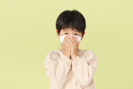 戴着口罩的小男孩用手捂住口鼻图片