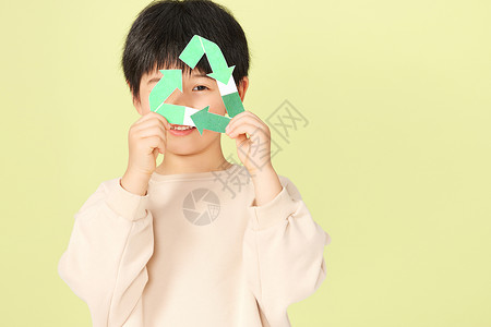 绿色折纸箭头拿着可回收标志的小男孩背景
