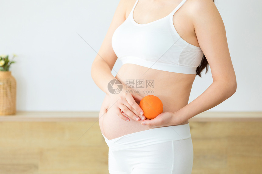 居家生活的孕妇拿着橘子图片