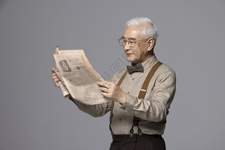 戴眼镜看报纸的老年人背景图片