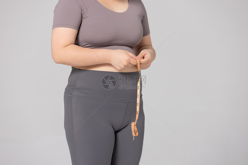 女性使用卷尺测量腰围的特写图片