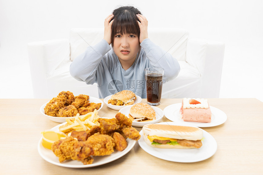 面对食物烦恼的肥胖女性图片