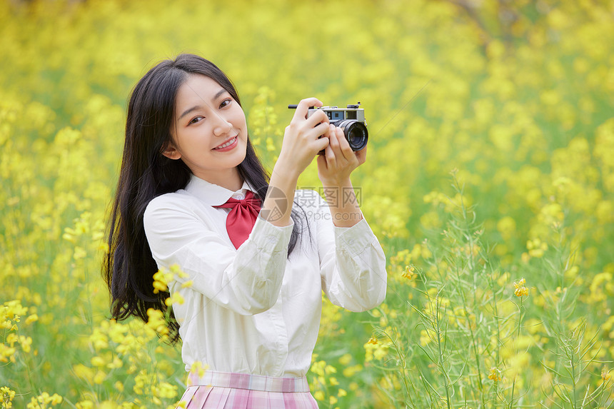 油菜花花海中的少女拍照图片