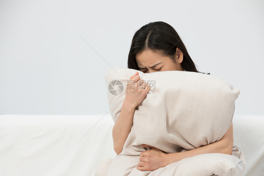 女性抱着枕头哭泣图片