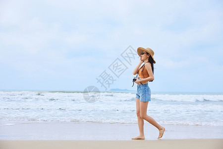 年轻美女手拿相机海边旅行高清图片