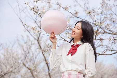 青春可爱美少女拿棉花糖逛游乐园背景图片