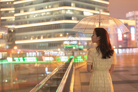 城市里撑着伞散步的女性背影图片