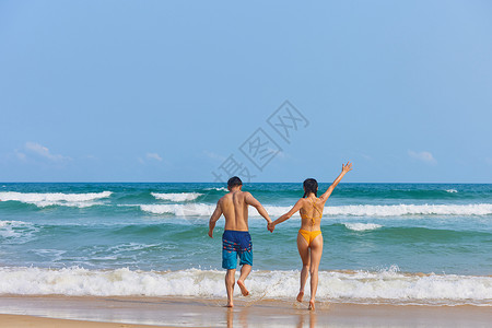 年轻情侣奔入大海背影图片