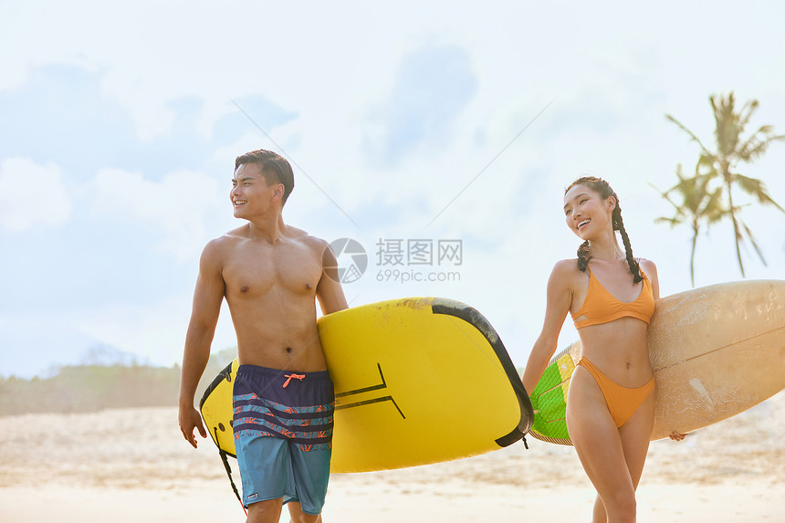 青年男女拿着冲浪板海边行走图片