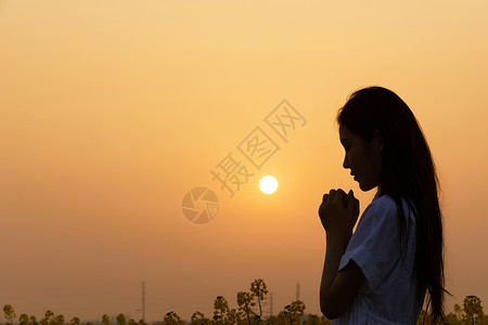 女性祈祷许愿夕阳下祈祷的女性剪影背景