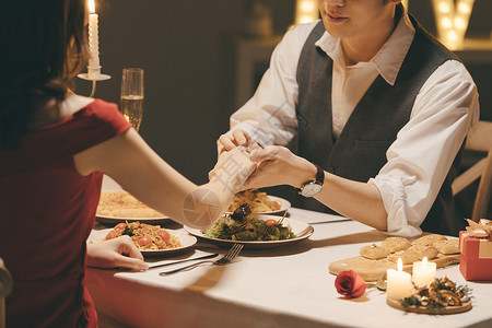 情侣坐在板凳上情人节情侣餐桌上戴戒指背景
