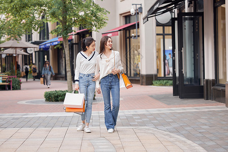 美女在商场购物闺蜜姐妹一起走在商业街上背景