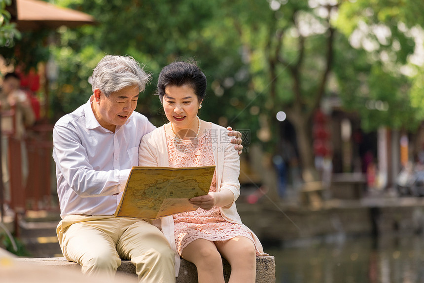 老年夫妻坐在河畔看地图图片