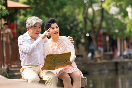 河畔的人老年夫妻坐在河畔看地图背景