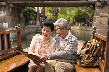 亚洲游旅行海报老年恩爱夫妻游船上看地图背景