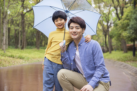 父子下雨天公园里撑伞高清图片