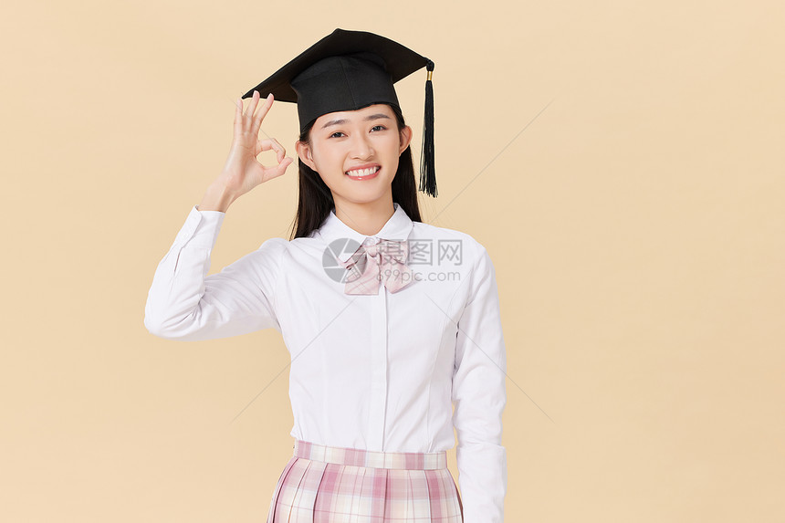 带着学位帽的女生手举毕业证书庆祝毕业