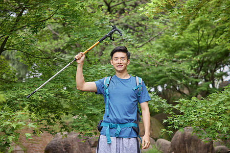 青年男性拿登山杖徒步背景图片