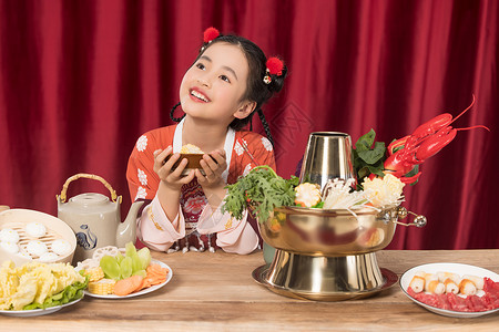 双手捧着饭碗餐桌前的小女孩背景图片