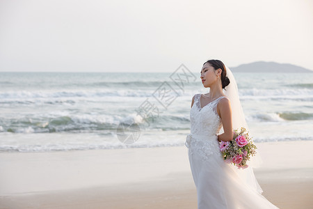 海边沙滩婚纱美女拿手捧花图片