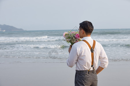 喜庆男性人像海边男性拿着手捧花看海背景