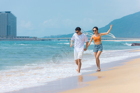 夏日戏水夏日情侣海边沙滩上嬉戏戏水背景