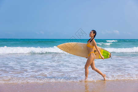 沙滩裤海边比基尼美女手拿冲浪板行走背景