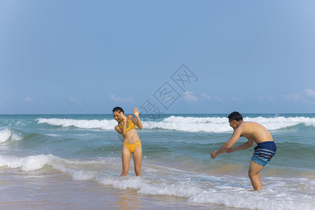 年轻泳装情侣海边戏水打闹高清图片