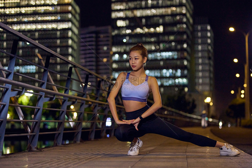 城市户外夜跑女性拉伸运动图片