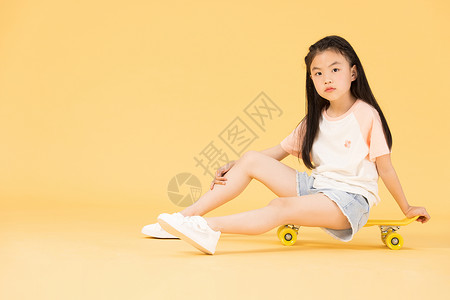 坐在滑板上的小女孩背景图片