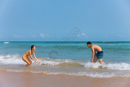 年轻泳装情侣海边戏水打闹高清图片