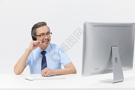 中年男客服在电脑上前打电话图片