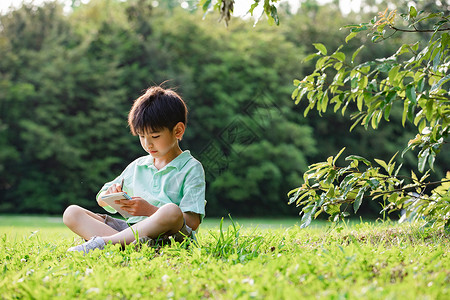 小男孩坐在草地上画面背景图片