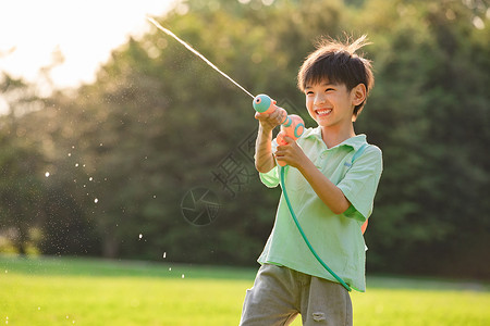 玩水枪的男孩子夕阳下开心玩水枪的小男孩背景