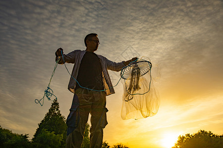 捕鱼季丰收夕阳下捕捞的渔民背景
