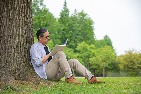中年男性在树下认真阅读看书图片