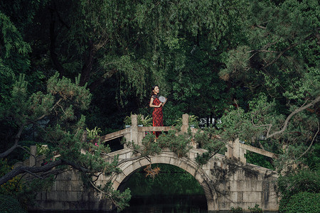 站在桥上手拿扇子的旗袍美女高清图片