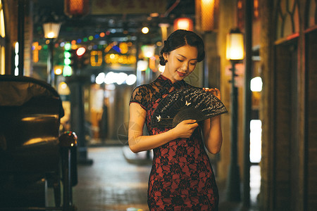 中式模特城市夜晚霓虹灯下手拿扇子的旗袍美女背景