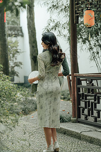 在园林里散步的旗袍美女背影背景图片