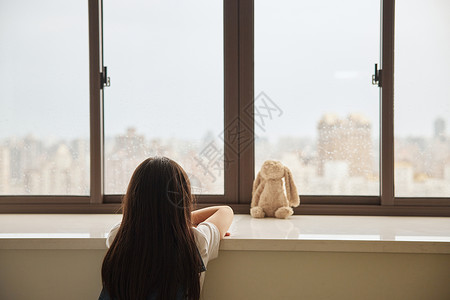 沮丧女孩站在窗前寂寞的小女孩背景