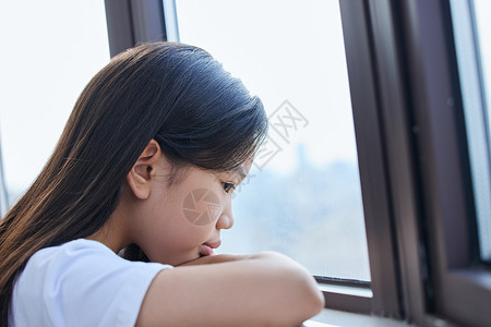 坐在窗前的女孩趴在窗前表情难过的小女孩背景