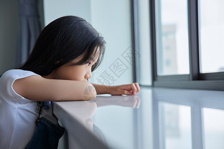 女孩沮丧孤单的留守儿童趴在窗边背景