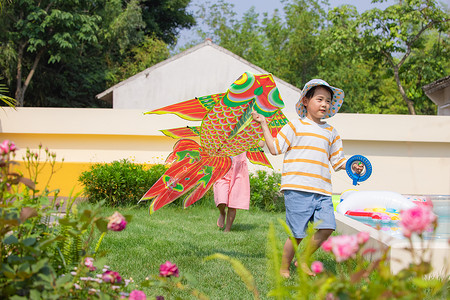 儿童拿着风筝在草坪上奔跑背景图片