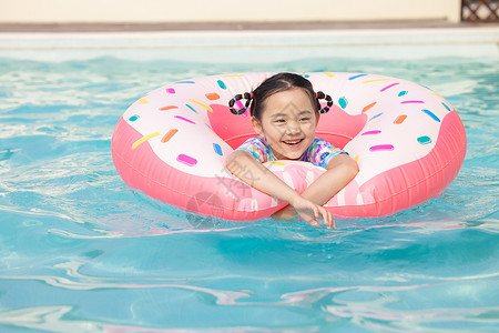 小女孩在泳池里面用游泳圈游泳高清图片