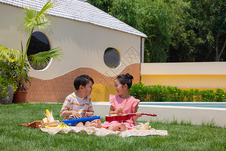 小朋友弹琴小男孩小女孩坐在野餐垫上玩尤克里里背景