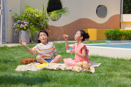 吹泡泡的女孩小男孩与小女孩草坪上野餐吹泡泡背景